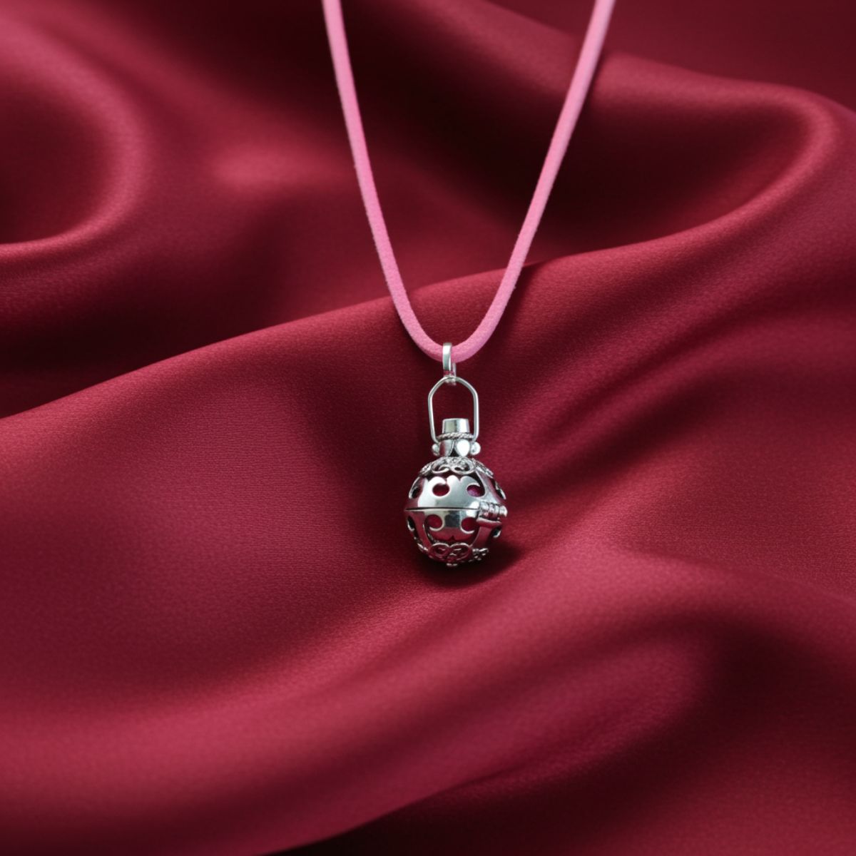 Silver pendant on a pink cord against a red satin background