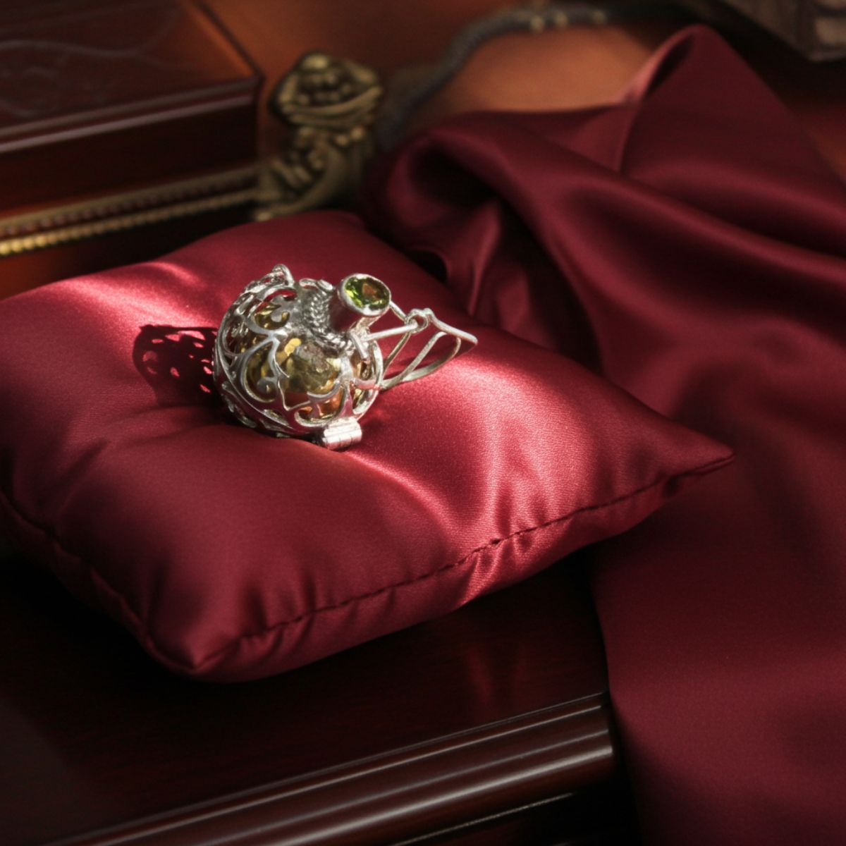 Silver ring with gemstones on a red satin pillow