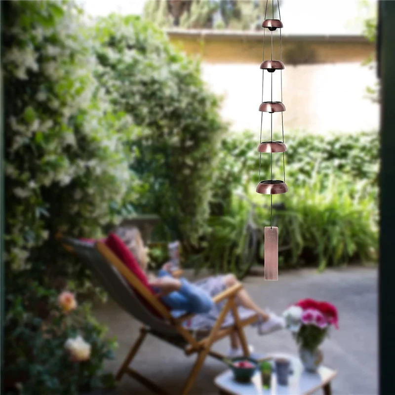 Outdoor setting with a person sitting on a chair, a hanging rain chain, and a blurred background of greenery.