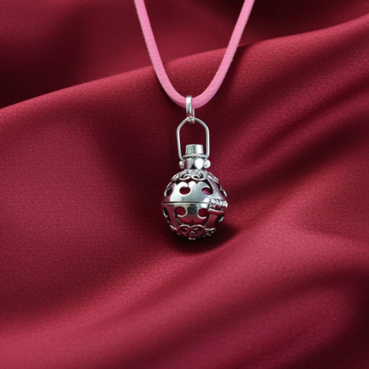 Silver pendant on a pink cord against a red fabric background