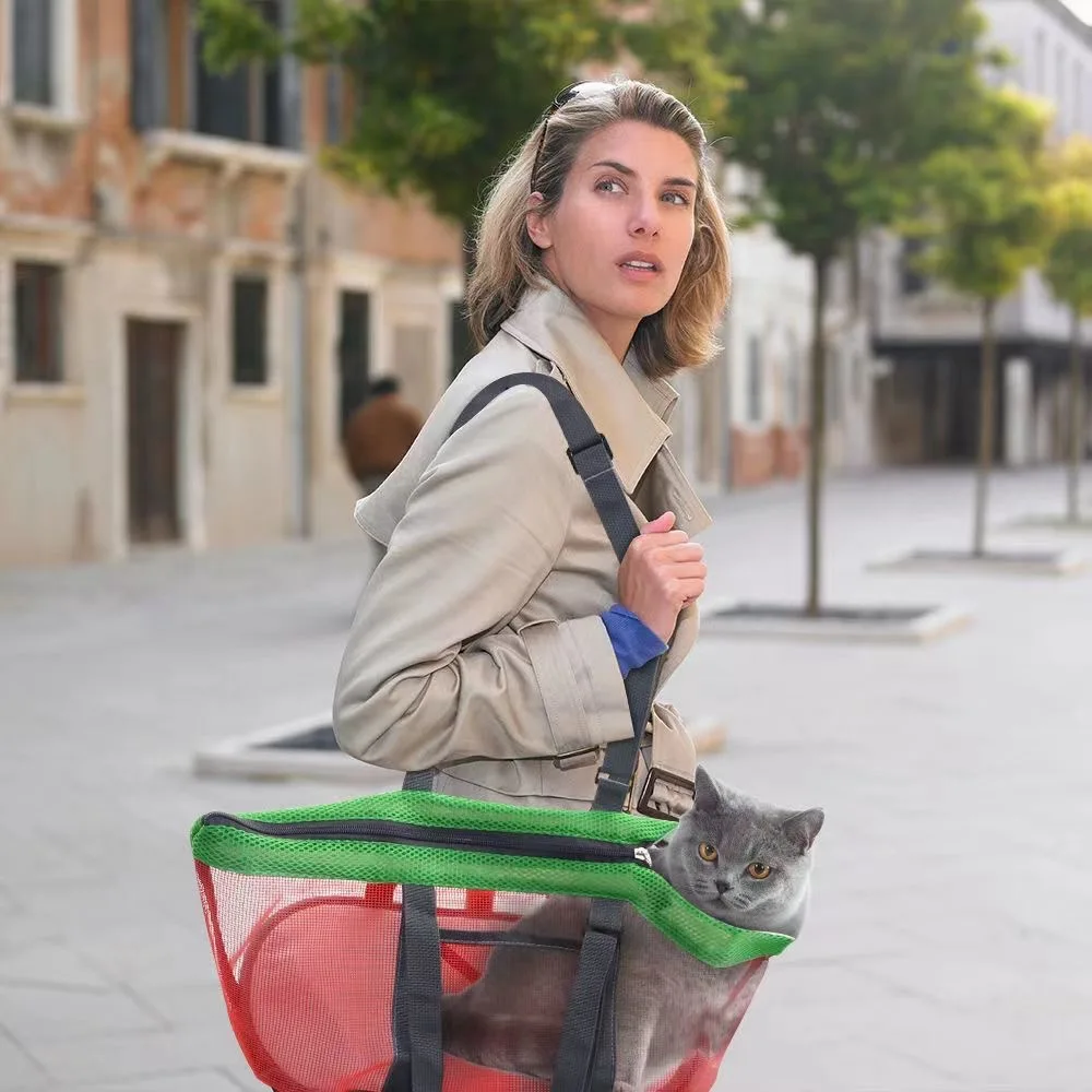 A woman in a beige trench coat walks on a quiet street, carrying a gray cat in the Pet Carrier Bags Mesh Foldable Pet Carrier Handbag Purse for Small Dogs. The cat peers out calmly as trees and old buildings blur in the background. Suitable for miniature breeds.