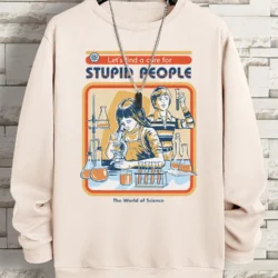 A beige Lets Find A Cure For Stupid People Sweatshirt hangs on a hanger against a brick wall. Its graphic shows two people in a science lab with the text “Let”™s find a cure for STUPID PEOPLE” and “The World of Science.” A silver chain necklace is draped over it.
