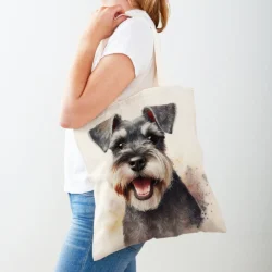A woman in a white T-shirt and blue jeans carries the Double Print Schnauzer Women Shopper Bag””a casual, foldable travel handbag featuring a smiling Schnauzer design, ideal for shopping or everyday use.
