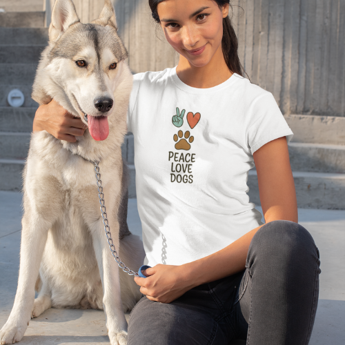 A smiling woman sits on steps with her leashed Siberian Husky, wearing a Peace Love Dogs T-Shirt. The happy, alert Husky poses beside his owner, who proudly shows off the Peace Love Dogs T-Shirt.