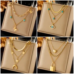 Layered gold pendant necklaces with butterfly, moon, blue eye, and lock charms displayed on beige background