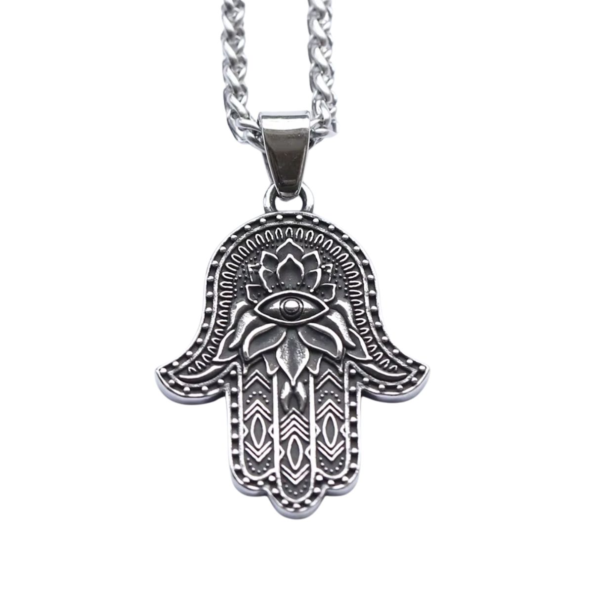 The Hamsa Hand of Fatima Pendant features a silver design with an engraved eye in the palm, lotus flower motifs, and detailed geometric lines, hanging gracefully from a chain.