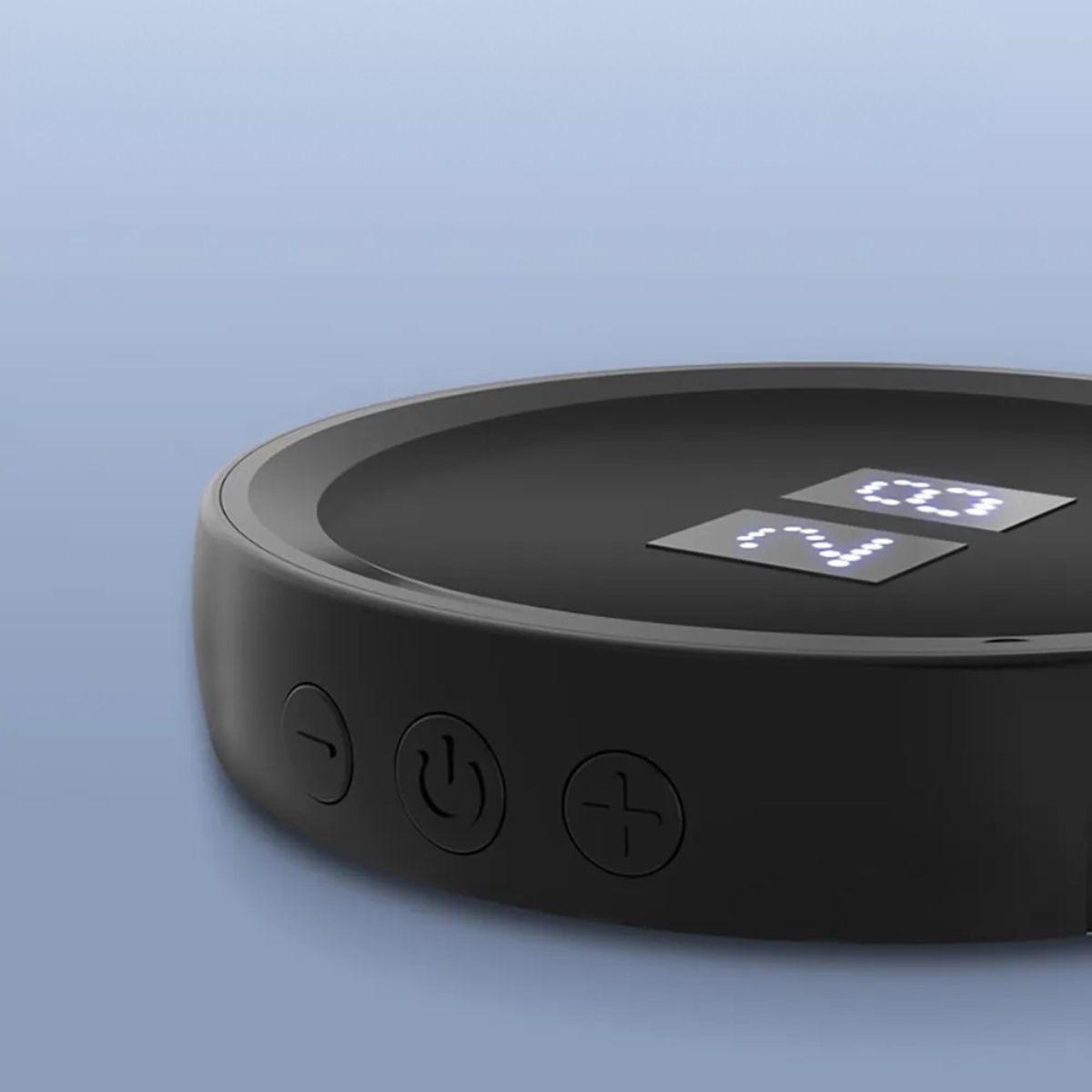 Close-up side view of black low-frequency pulse relaxation device showing control buttons.