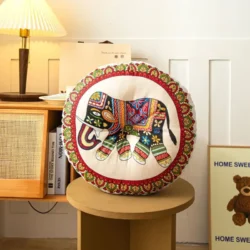 Round bohemian-style cushion featuring a colourful embroidered elephant design on a cream base with decorative border detailing.