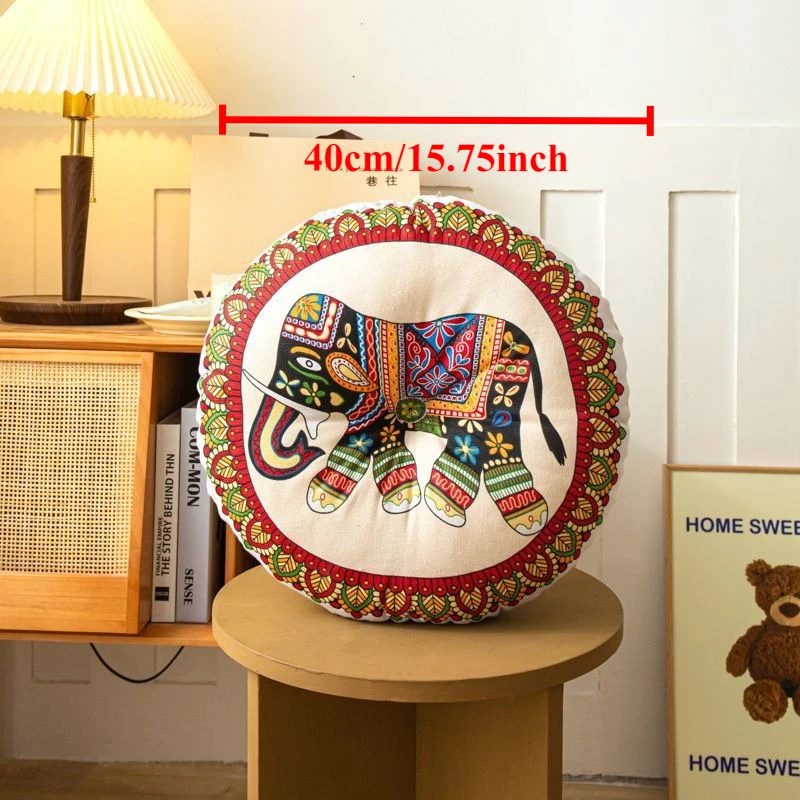 Round bohemian-style cushion featuring a colourful embroidered elephant design on a cream base with decorative border detailing.