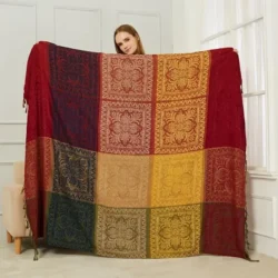 Large boho plaid chenille blanket draped over a cream sofa, featuring rich red, gold, and blue patterned squares in a peaceful home setting.