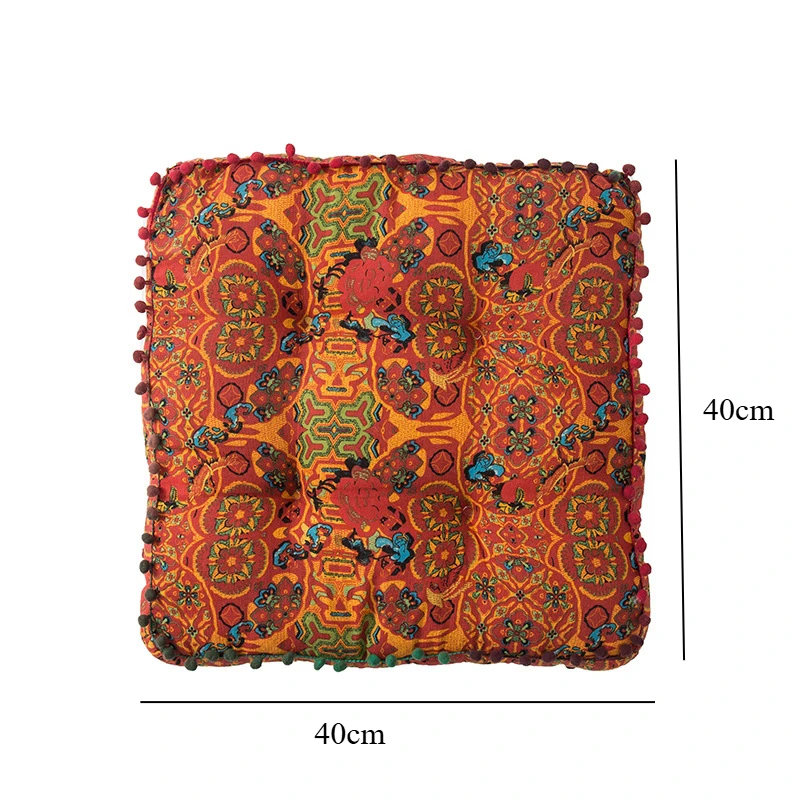 Square orange bohemian-style cushion with colourful patterned fabric and pom-pom trim around the edges. shown with measurements.