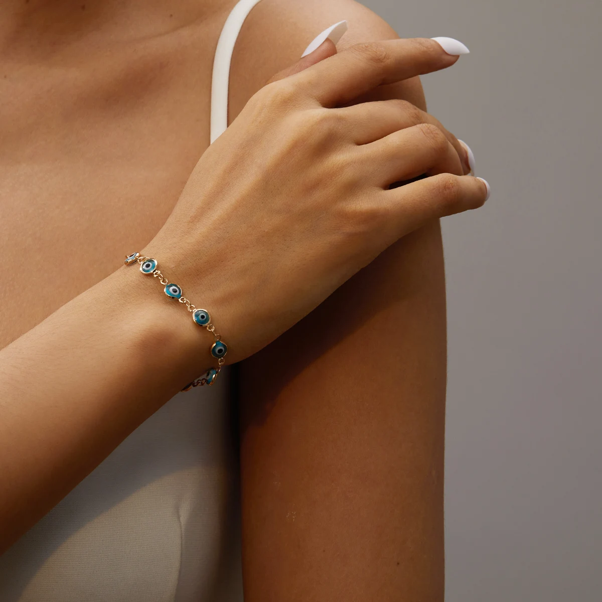Elegant gold bracelet with small blue Turkish evil eye charms symbolising calm and protection on a woman’s wrist.