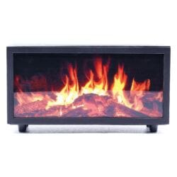 A rectangular, black electric fireplace with a glass front features a vivid orange and yellow flame effect over fake logs. The unit, resembling a flame-effect-aroma-diffuser-bird-sound device, stands on four short legs against a plain white background.