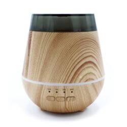 A rounded, wood-grain USB aroma diffuser with a black-tinted top. It features a colour change option, a horizontal white light line around its center, and three buttons labeled ON, 1H, 3H, and 6H for timer settings. The background is white.
