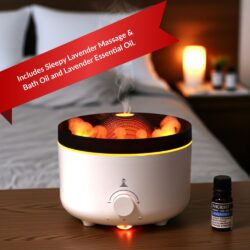 The Large Volcano Effect Aroma Sleep Kit diffuser emits steam and orange light on a bedside table, next to a lavender essential oil bottle. The background shows a bed, a lit candle, and a banner stating: Includes Aroma Sleep Kit essentials.
