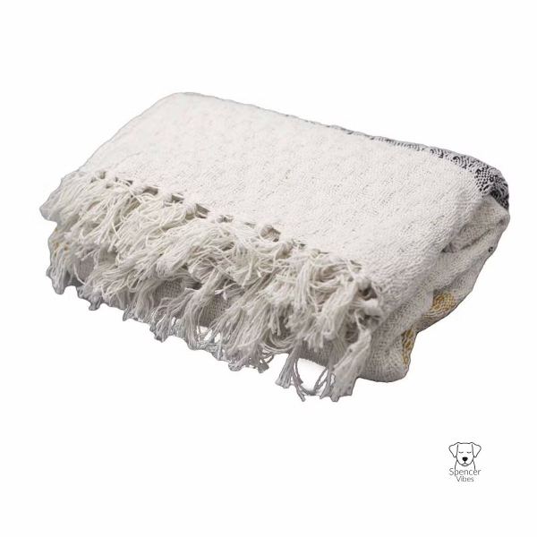 The Boho Cotton Throw Blanket – Mellow Mattala Neutral Stripe features a thick, soft off-white fabric with textured patterns, long fringes, and a small Spencer Vibes dog face logo on the bottom right corner.