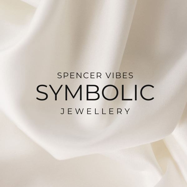 Soft, white fabric is draped in gentle folds as a background. Centered, black text reads: SPENCER VIBES SYMBOLIC JEWELLERY. The elegant, minimalistic style suggests sophisticated luxury with a focus on meaningful symbolic jewellery.